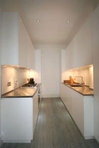 White lacquered Kitchen with handle groove detailing.  Glass splash-backs and stainless steel worksurfaces