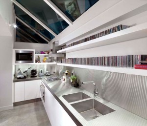 White lacquered Kitchen with handle groove detailing, integral under-shelf lighting.  Stainless steel worksurfaces and splashbacks.